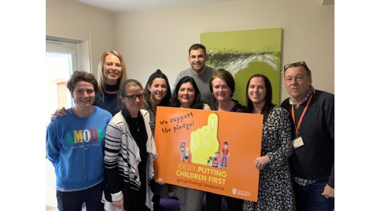 A group of people hold a 'putting children first' sign 