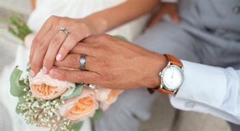 Two people holding hands with wedding rings on