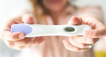 Woman holding positive pregnancy test